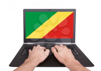 Hands working on laptop showing on the screen the flag of Conga