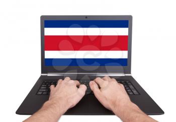 Hands working on laptop showing on the screen the flag of Costa Rica