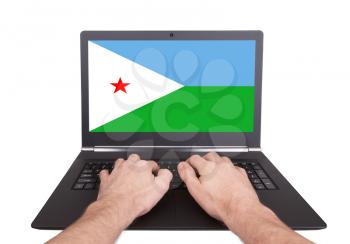 Hands working on laptop showing on the screen the flag of Djibouti