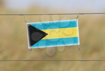 Border fence - Old plastic sign with a flag - Bahamas