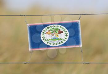 Border fence - Old plastic sign with a flag - Belize