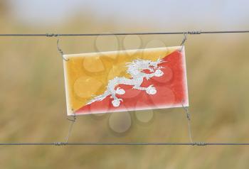 Border fence - Old plastic sign with a flag - Bhutan