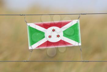 Border fence - Old plastic sign with a flag - Burundi