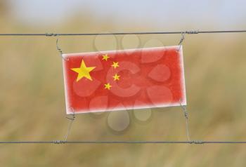 Border fence - Old plastic sign with a flag - China