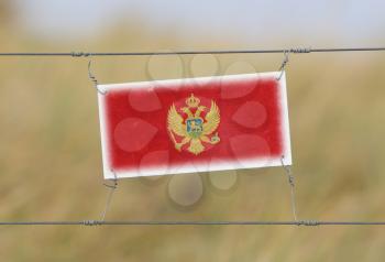 Border fence - Old plastic sign with a flag - Montenegro