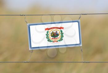 Border fence - Old plastic sign with a flag - West Virginia