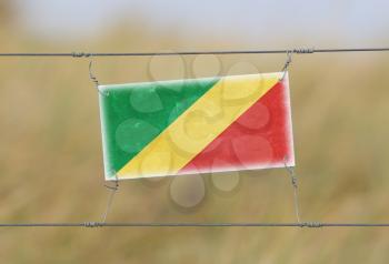 Border fence - Old plastic sign with a flag - Congo