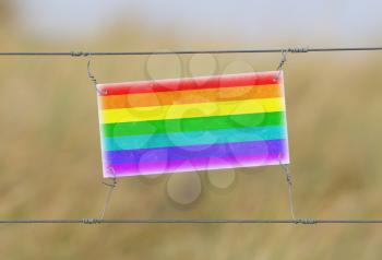 Border fence - Old plastic sign with a flag - Rainbow flag