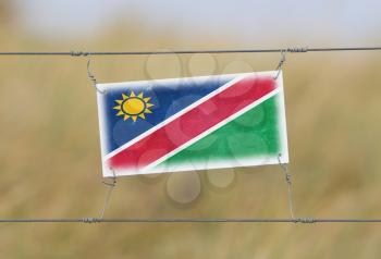 Border fence - Old plastic sign with a flag - Namibia