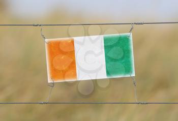 Border fence - Old plastic sign with a flag - Ivory Coast