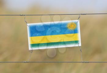 Border fence - Old plastic sign with a flag - Rwanda