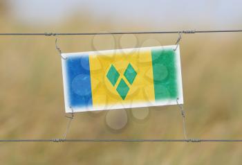 Border fence - Old plastic sign with a flag - Saint Vincent and the Grenadines