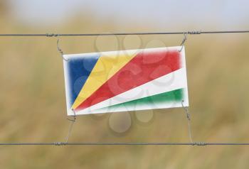 Border fence - Old plastic sign with a flag - Seychelles