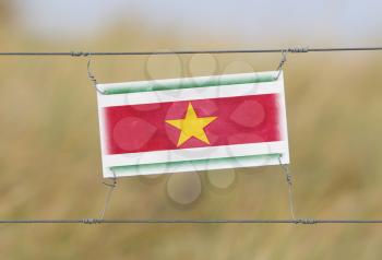 Border fence - Old plastic sign with a flag - Suriname