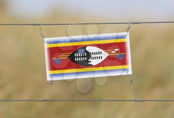Border fence - Old plastic sign with a flag - Swaziland