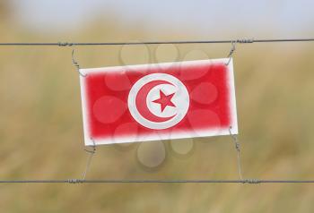 Border fence - Old plastic sign with a flag - Tunisia