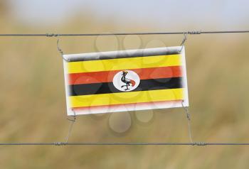 Border fence - Old plastic sign with a flag - Uganda