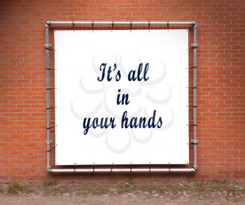Large banner with inspirational quote on a brick wall - It's all in your hands
