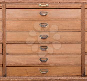 Row of large drawers with empty tags in an old furniture module
