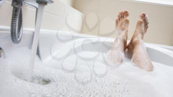 Men's feet in a bright white bathtub, selective focus on toes