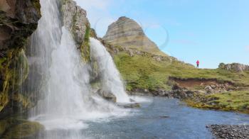 Kirkjufellsfoss waterfall near the Kirkjufell mountain on the north coast of Iceland's Snaefellsnes peninsula, unrecognisable woman