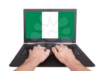 Hands working on laptop showing on the screen the flag of Nigeria
