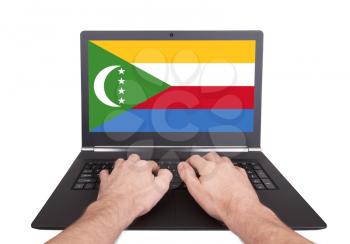 Hands working on laptop showing on the screen the flag of Comoros