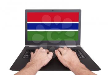 Hands working on laptop showing on the screen the flag of Gambia