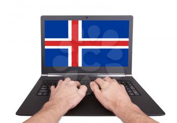 Hands working on laptop showing on the screen the flag of Iceland