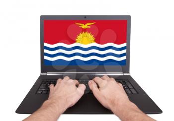 Hands working on laptop showing on the screen the flag of Kiribati