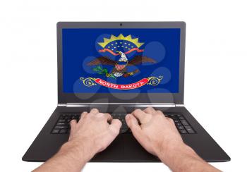 Hands working on laptop showing on the screen the flag of North Dakota