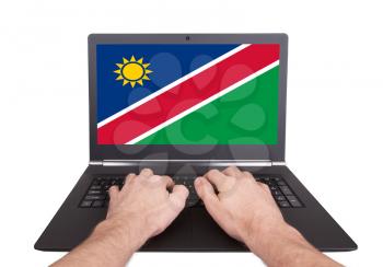 Hands working on laptop showing on the screen the flag of Namibia