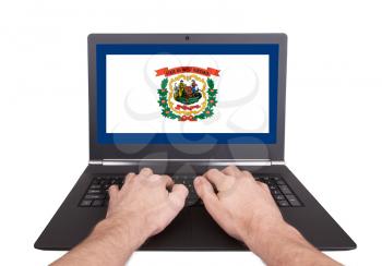 Hands working on laptop showing on the screen the flag of West Virginia