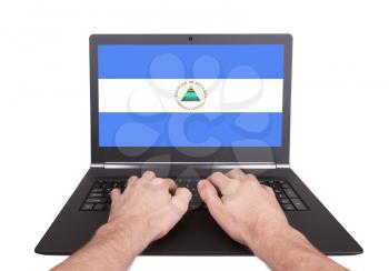 Hands working on laptop showing on the screen the flag of Nicaragua