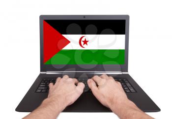 Hands working on laptop showing on the screen the flag of Western Sahara