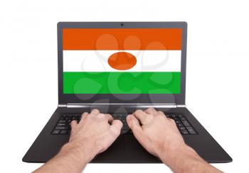Hands working on laptop showing on the screen the flag of Niger