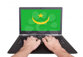 Hands working on laptop showing on the screen the flag of Mauritania