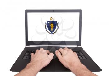 Hands working on laptop showing on the screen the flag of Massachusetts