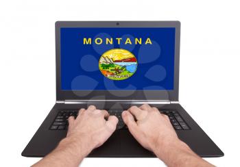 Hands working on laptop showing on the screen the flag of Montana