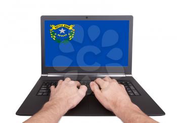 Hands working on laptop showing on the screen the flag of Nevada