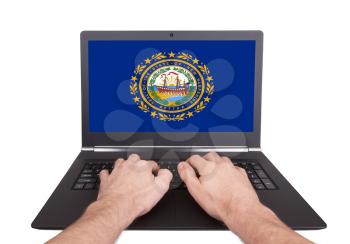 Hands working on laptop showing on the screen the flag of New Hampshire