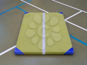 Very old yellow mat on a blue court, school gym