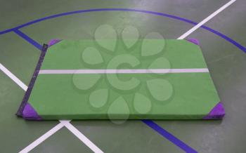 Very old green mat on a blue court, school gym