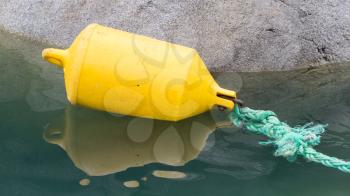 Inflatable yellow fender attached to a green rope