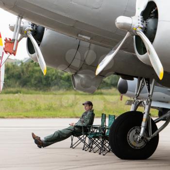 LEEUWARDEN, THE NETHERLANDS - JUNE 11, 2016: Pilot sitting under an old airplane during the open days of the dutch air force at Leeuwarden, the Netherlands on june 11, 2016.