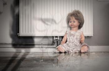 Abandoned doll sitting on a concrete floor