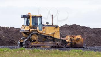 Yellow bulldozer in the field, construction in Iceland