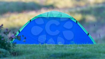 Small blue tent on a field of grass