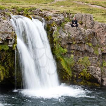 Kirkjufellsfoss waterfall near the Kirkjufell mountain on the north coast of Iceland's Snaefellsnes peninsula, woman enjoying the view