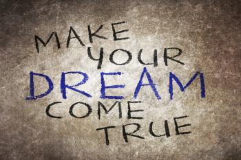 Make your dream come true - motivational slogan handwritten with white chalk on blackboard